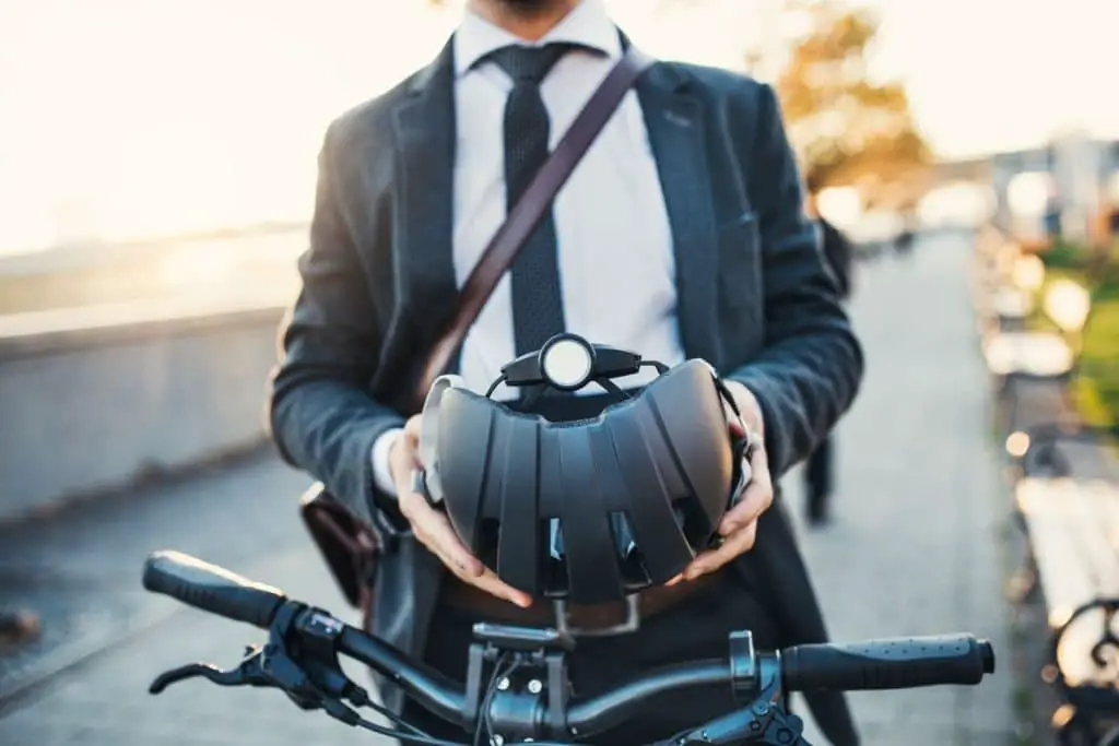 A man in a business suit holding a bicycle helmet