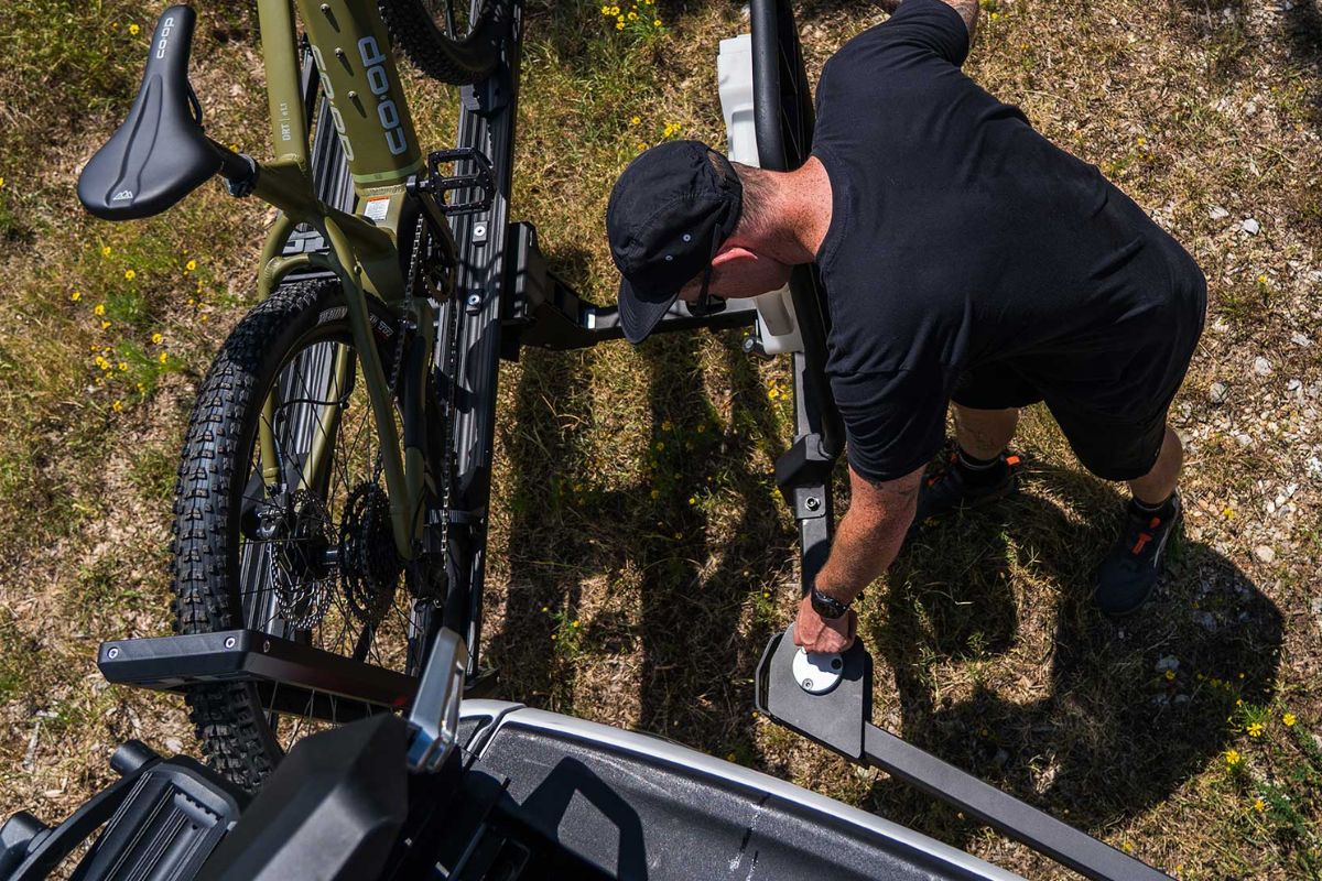 Person operating a hitch-mounted bike rack swung out for full vehicle rear access