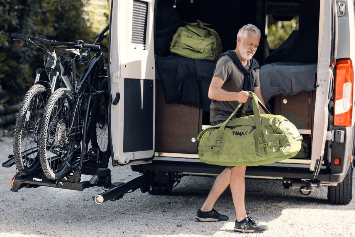 Man accessing camper van rear door with Thule VeloSwing bike rack swung open